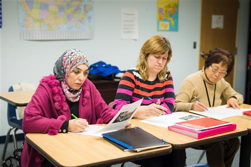 Adult English language learners study in class. 